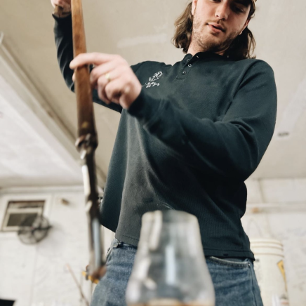 A person taking out bourbon from a barrel.